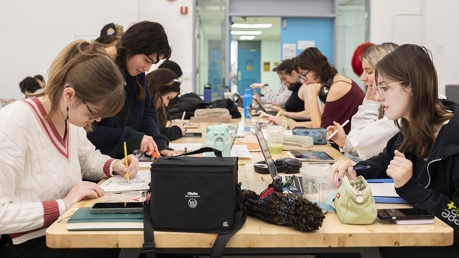 Students huddled around a table drawing.