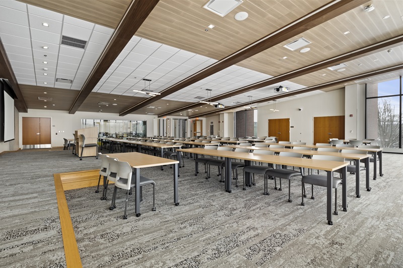 a large meeting room with long tables and chairs and a podium.