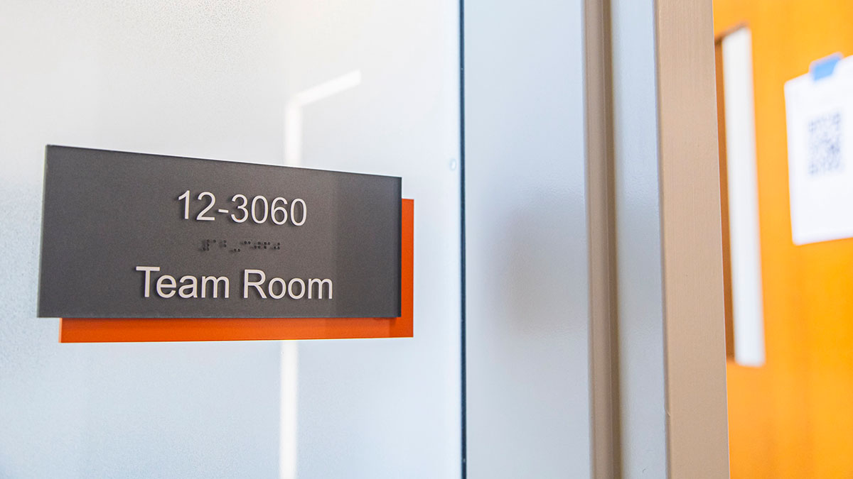 a sign on a glass wall that reads, 12 dash 30 60, team room