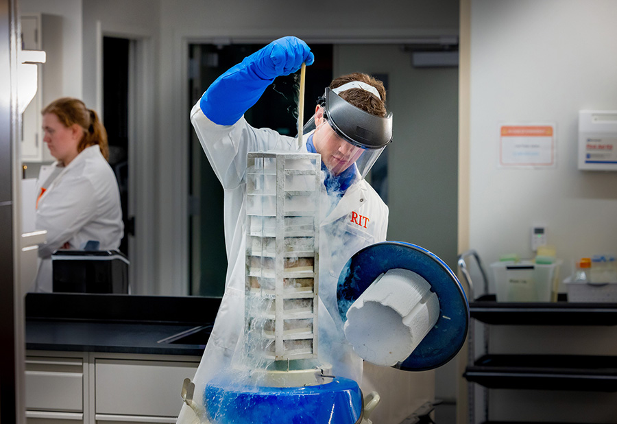 A student pulling equipment out of a liquid nitrogen container.