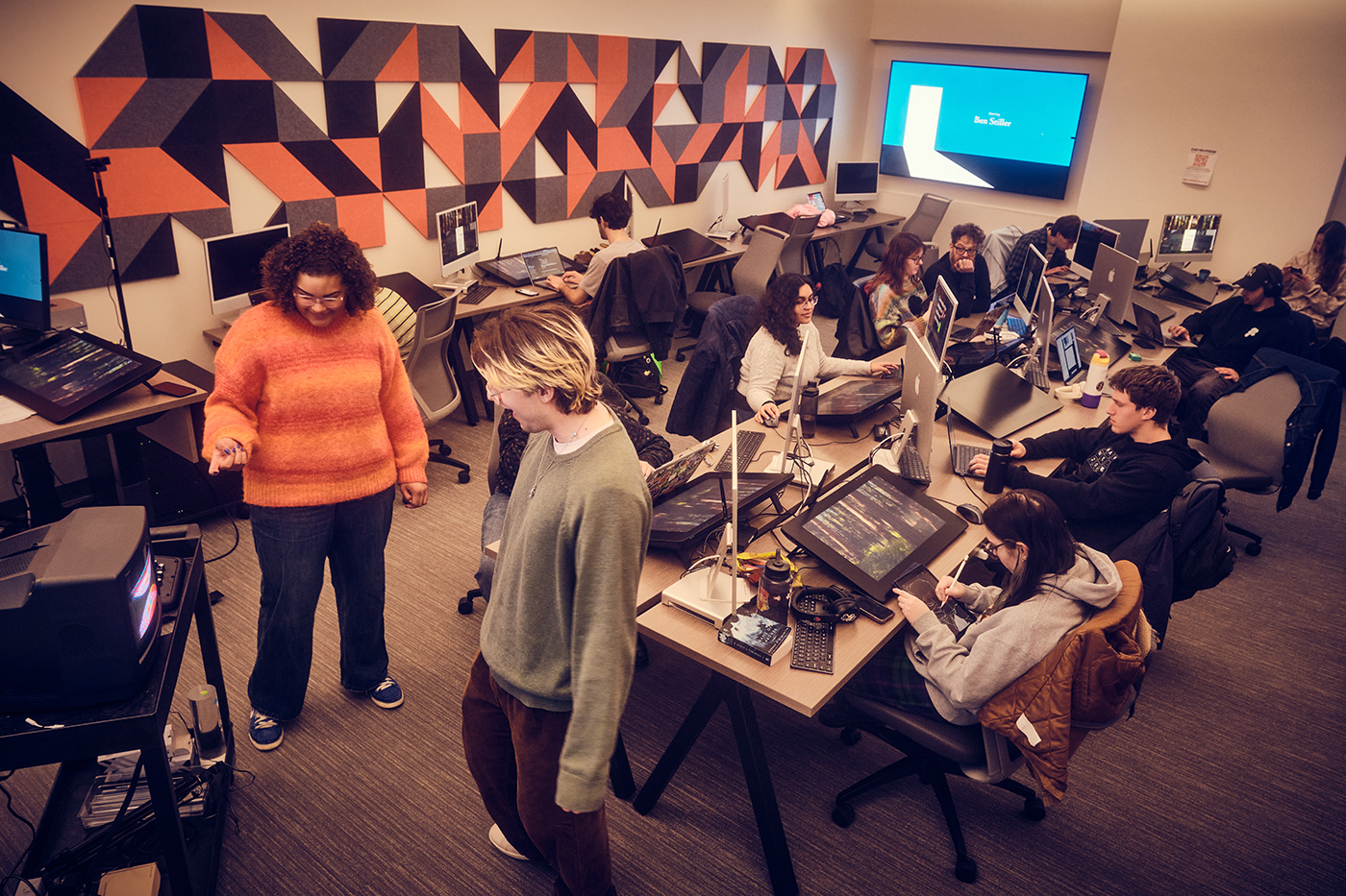 A class of students work at a computer in a lab.