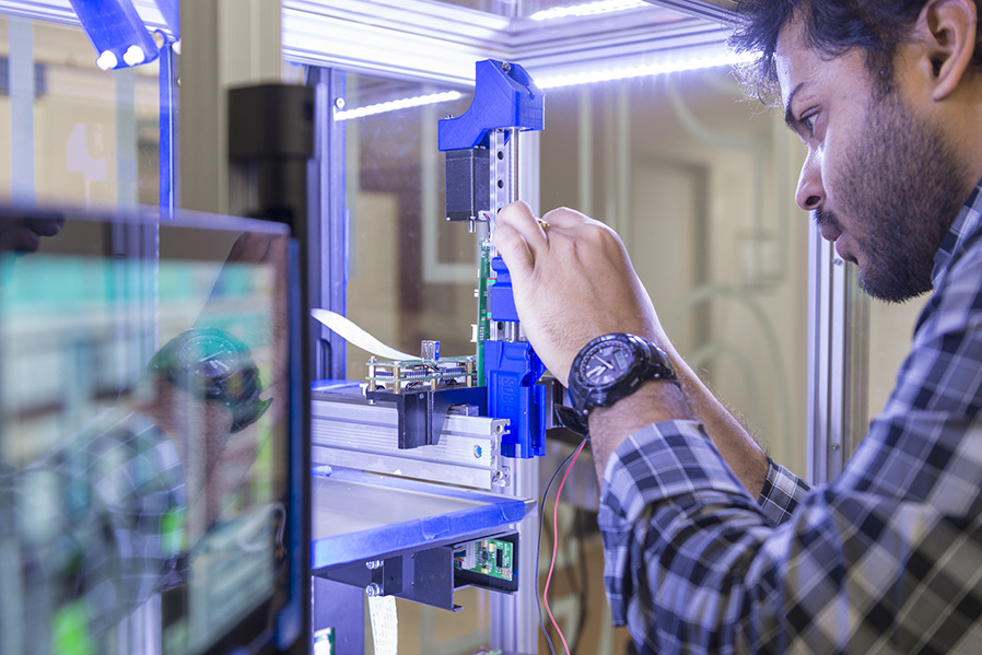 A close up of a student working with a machine in the AMPrint Center.