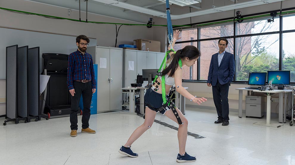 A student wearing and testing motion assessment technology while a student and faculty member observe the movements.