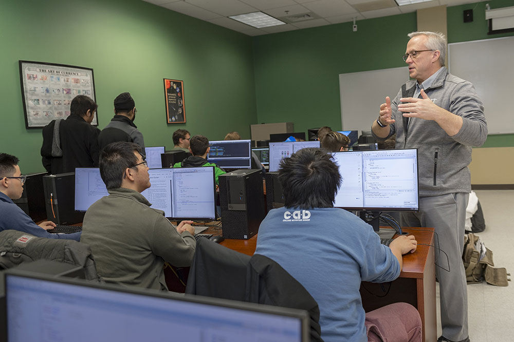 Professor teaching students who are sitting at computers.