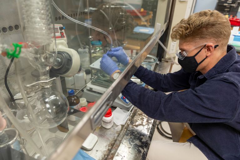 Student with gloves working with lab equipment.