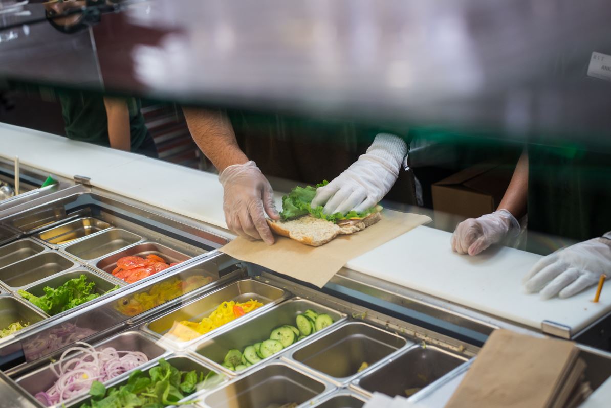 sub station at brick city cafe, someone putting lettuce on sandwich bread