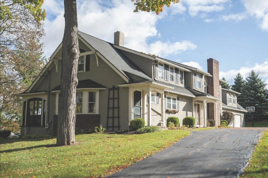 exterior of a two-story house with two brick chimneys and two covered entrances.