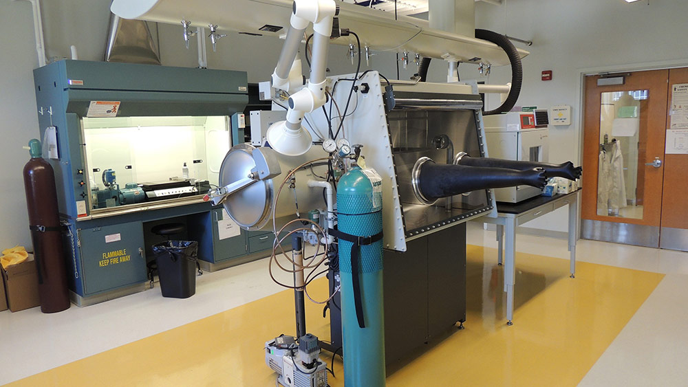 lab with specialized equipment, including a machine with gloves and a large cylindrical container.