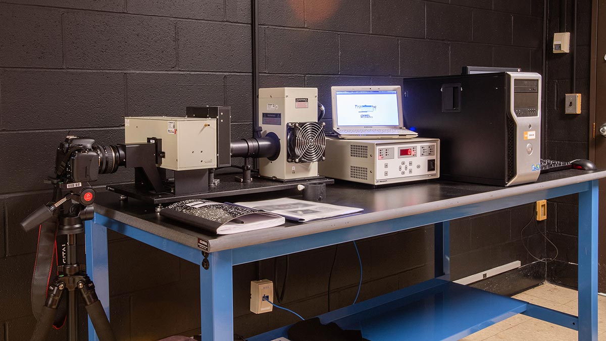 A piece of scientific lab equipment on a desk with a camera on the end.