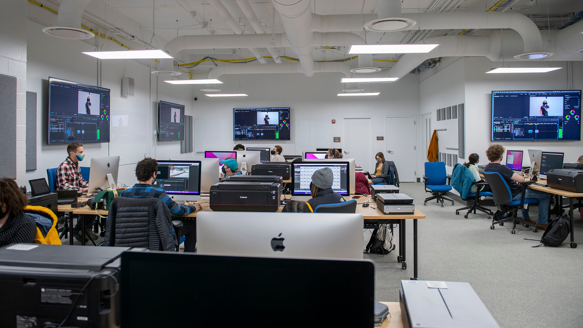 a computer lab with Mac computers with students working on them.