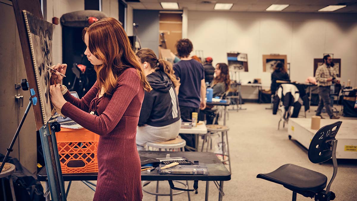 A group of students drawing at easels in a studio space.