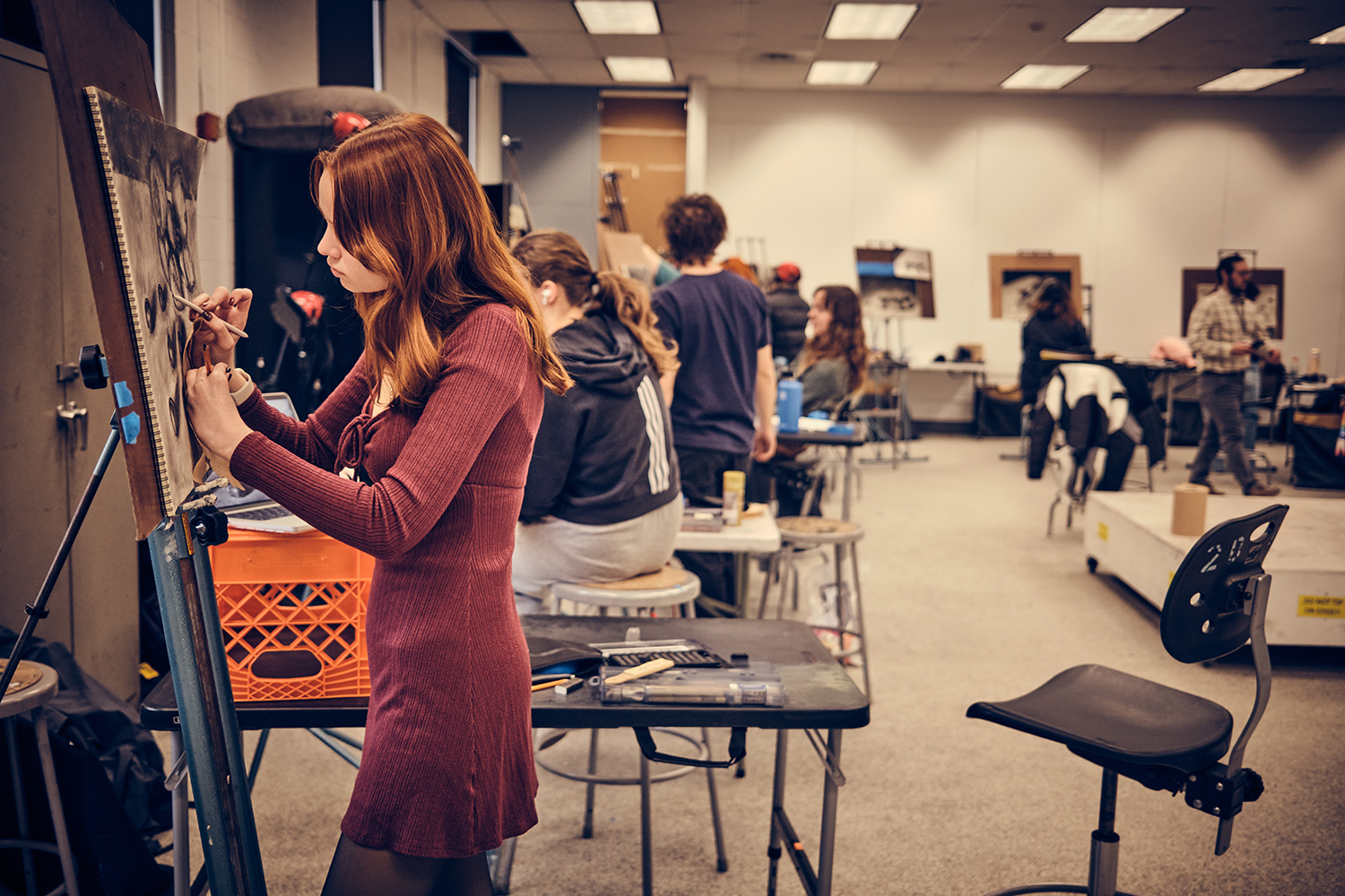 A group of students drawing at easels in a studio space.