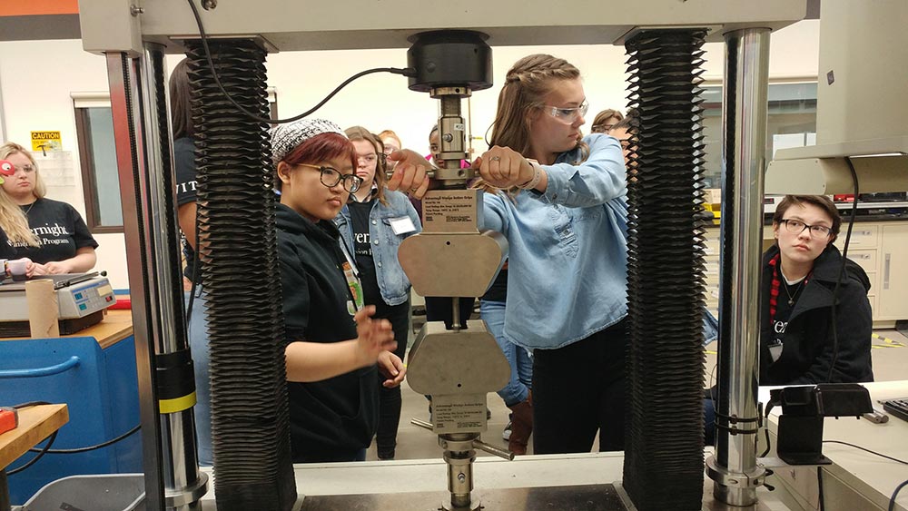 A group of students work with a large piece of lab equipment.