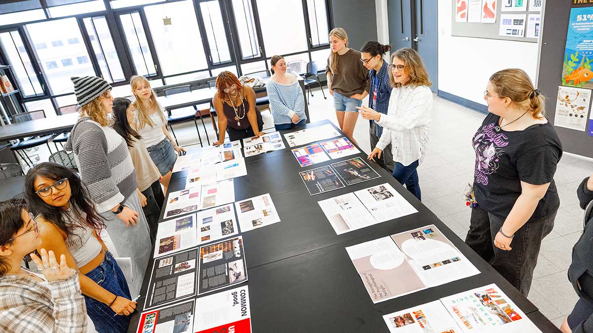 students gather around a large table with samples of magazine spreads.