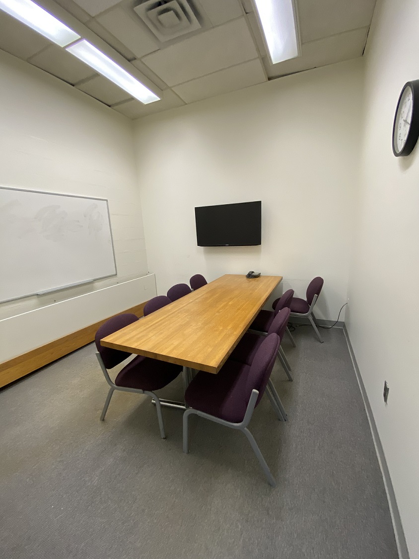 Small room with a conference table, tv, and whiteboard
