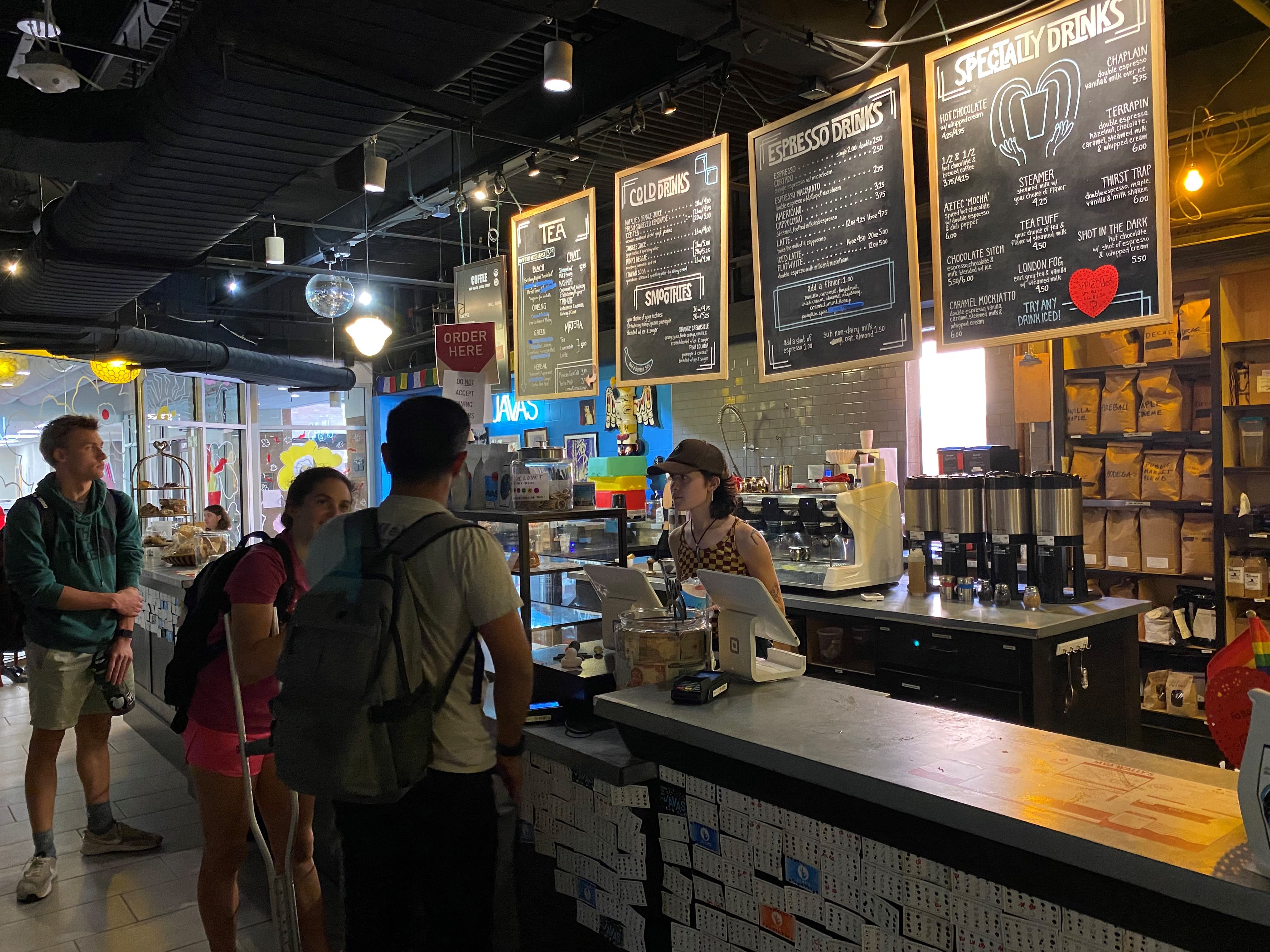 Students ordering at the Java's counter with menu behind cashier 
