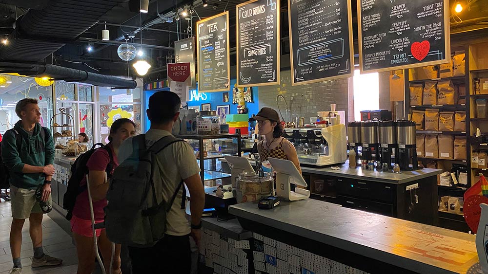 Students ordering at the Java's counter with menu behind cashier.