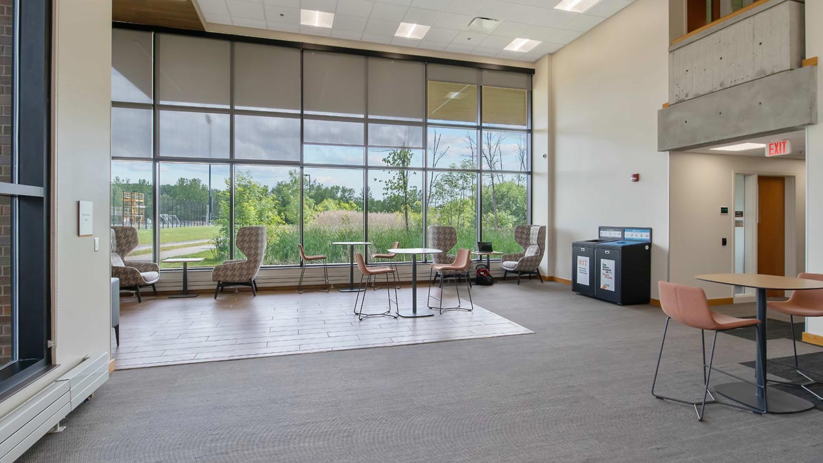 an atrium space with floor to ceiling windows and a variety of seating.