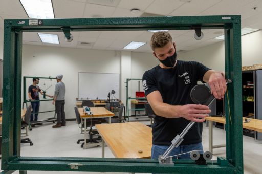 Student works on equipment with measuring tool.