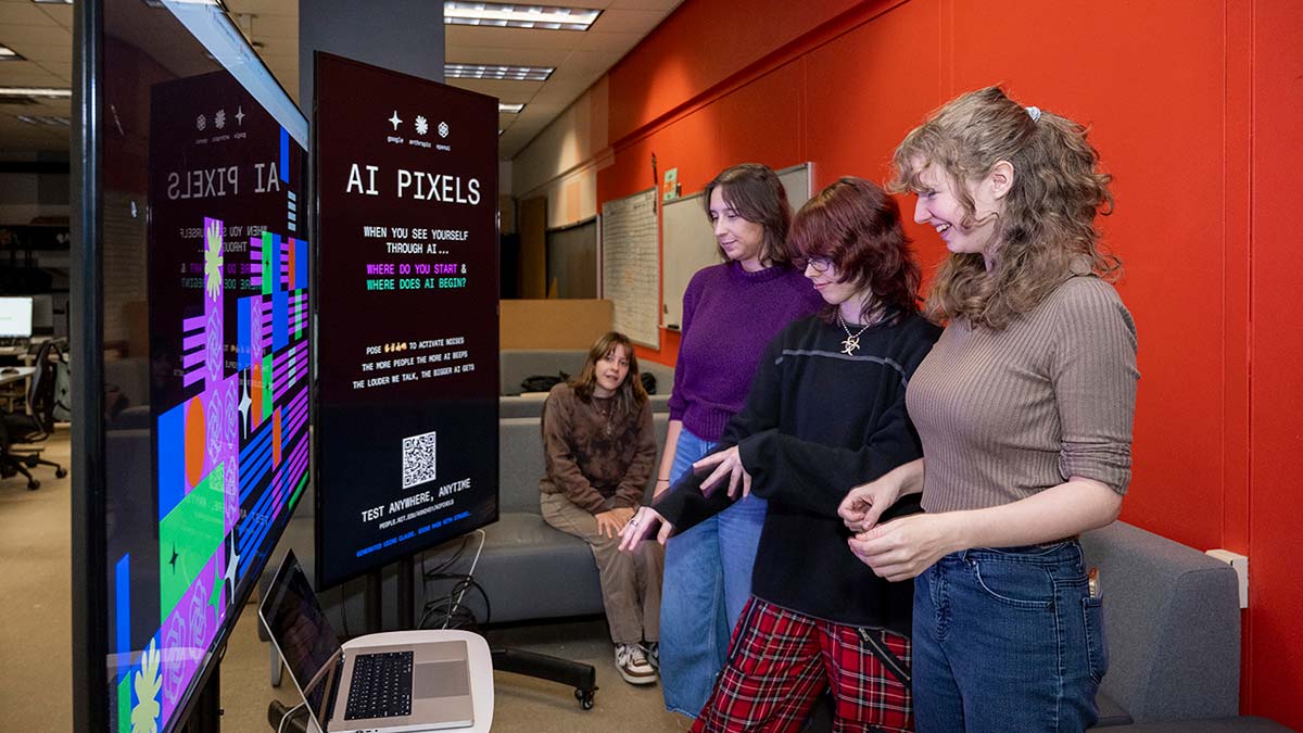 Students look at large touchscreen displays.