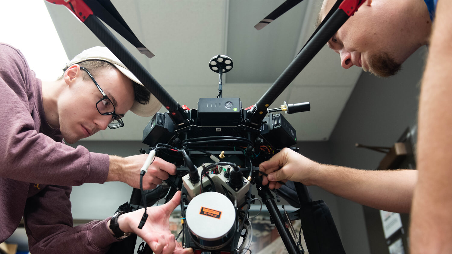 two students making adjustments to a drone.