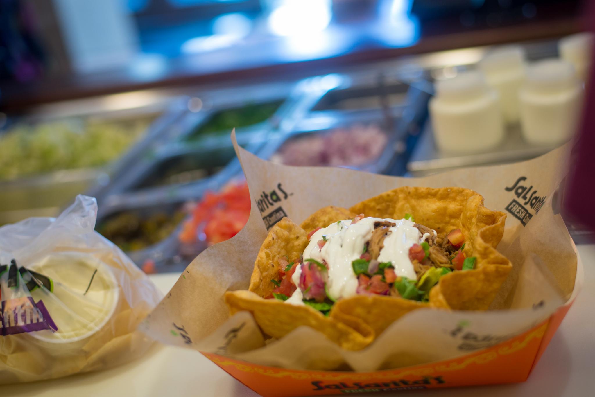 A taco bowl with a buffet line in the background