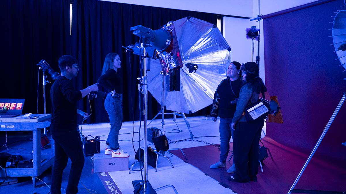 students working with photo equipment in a room in blue lighting.