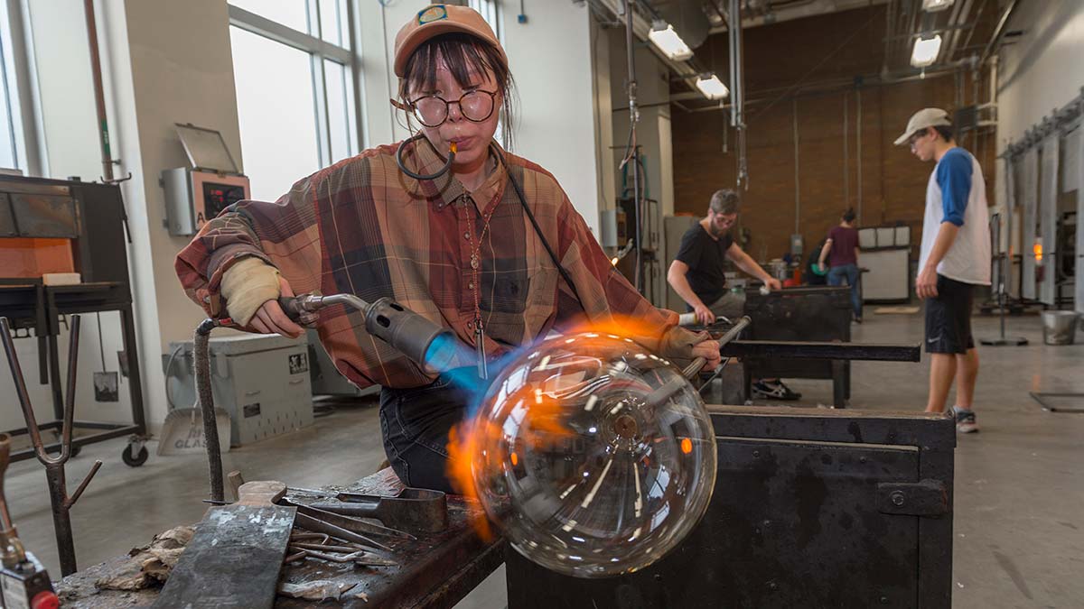 A student lights a torch to a glass object.