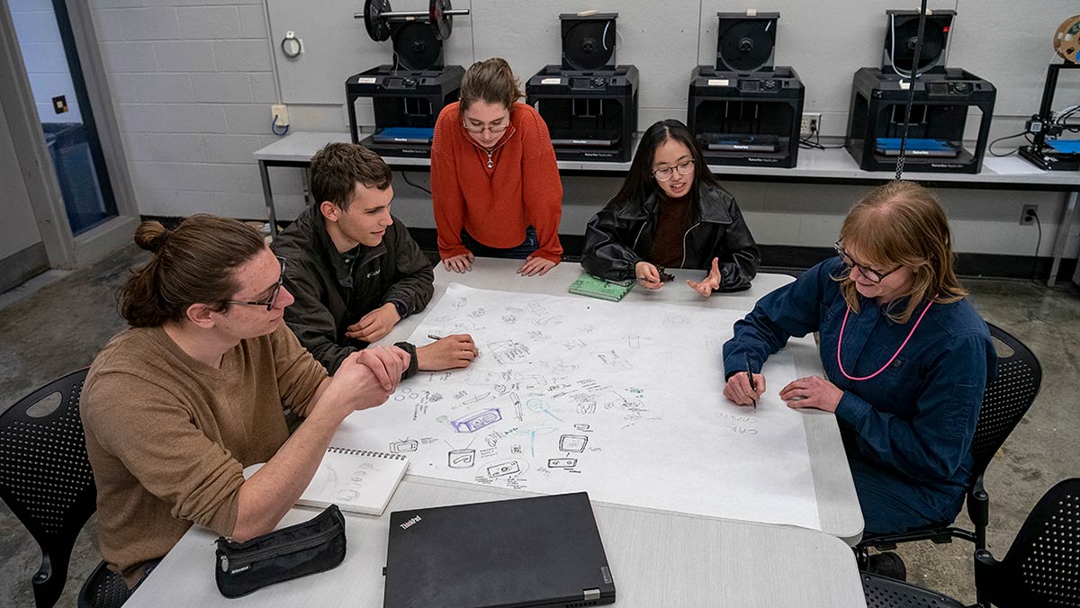 A group of students in a studio sketching on large paper.