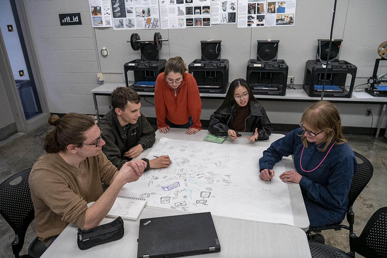 A group of students in a studio sketching on large paper.