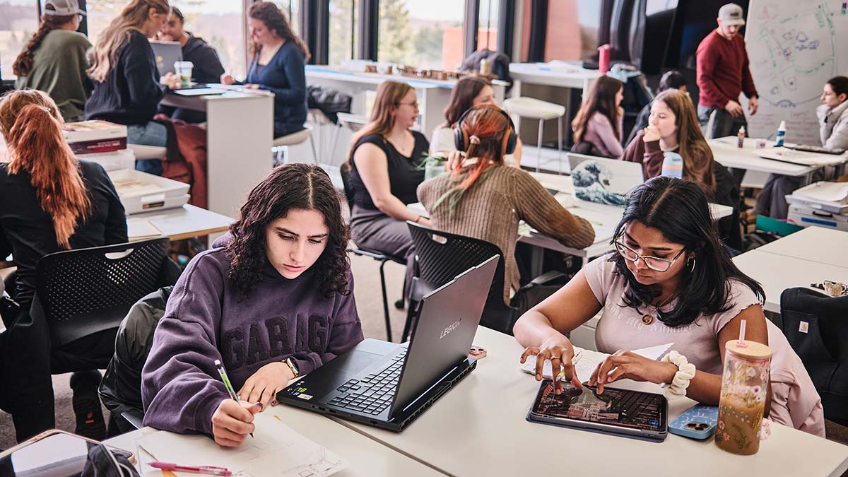 students work at tables in a large room.