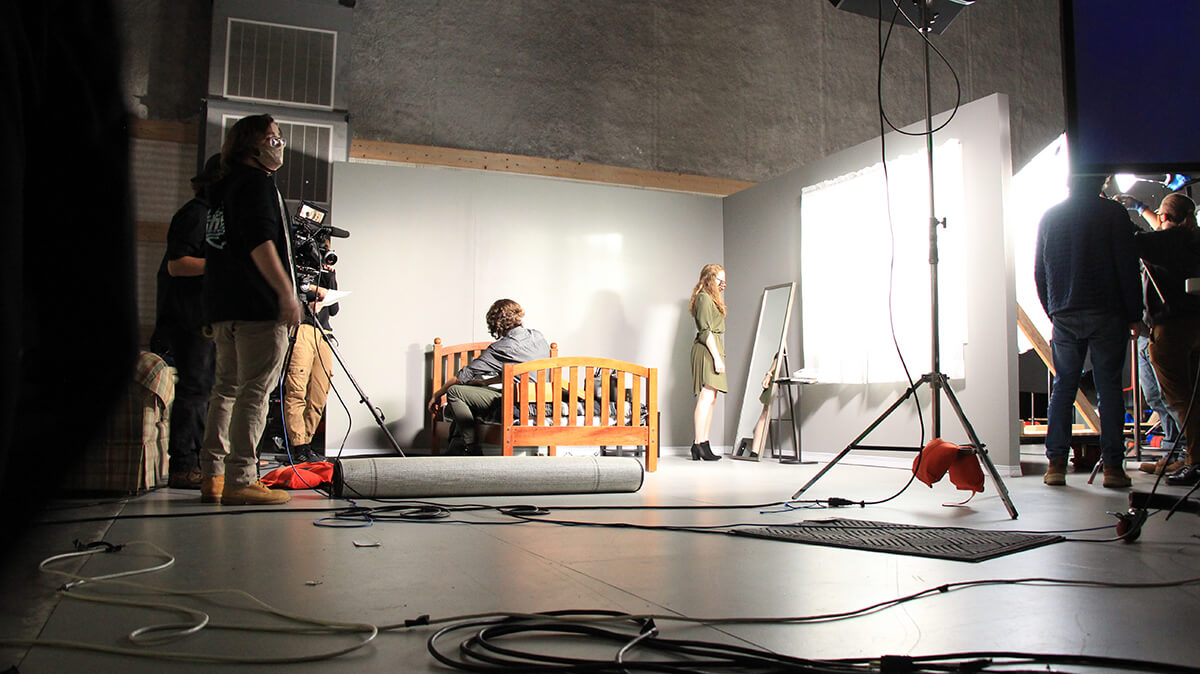 a scene in a sound studio with student actors sitting on a bed and looking at a mirror.