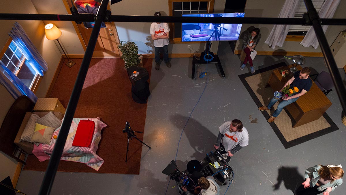overhead view of the soundstage, which is set up like a bedroom, with several students working with cameras and props.