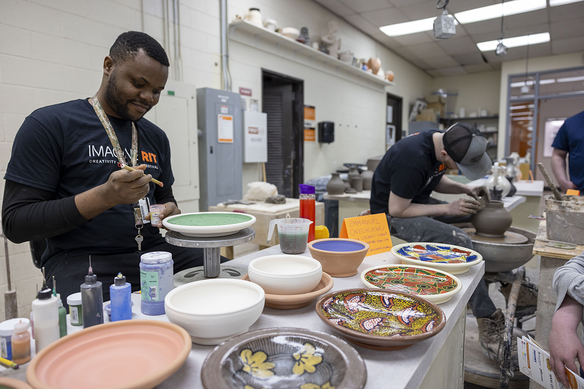 A ceramics MFA student paints a vessel he made.