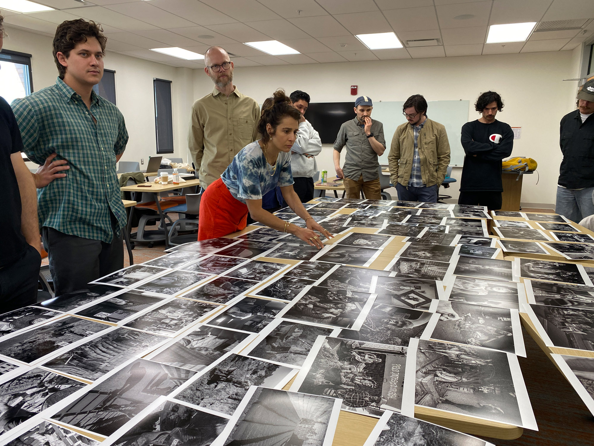 People look at photo prints spread across a table.