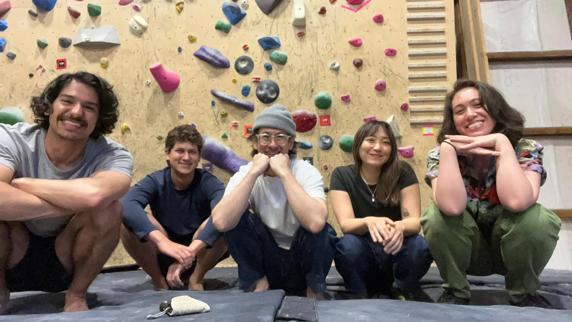 A group of people in front of a rock-climbing wall.