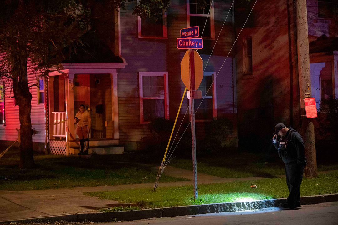 A civilian technician officer with a flashlight at an intersection at night.