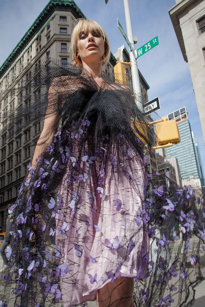 woman modeling dress with black fabric overlay and small purple butterflies.