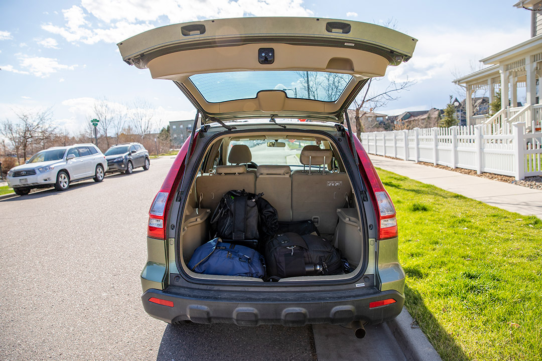 opened back end of SUV with duffel bags and backpacks inside.