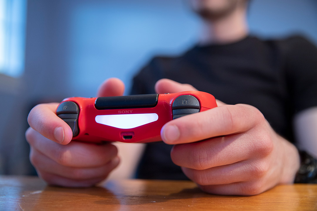 closeup of hands holding a red video game controller.