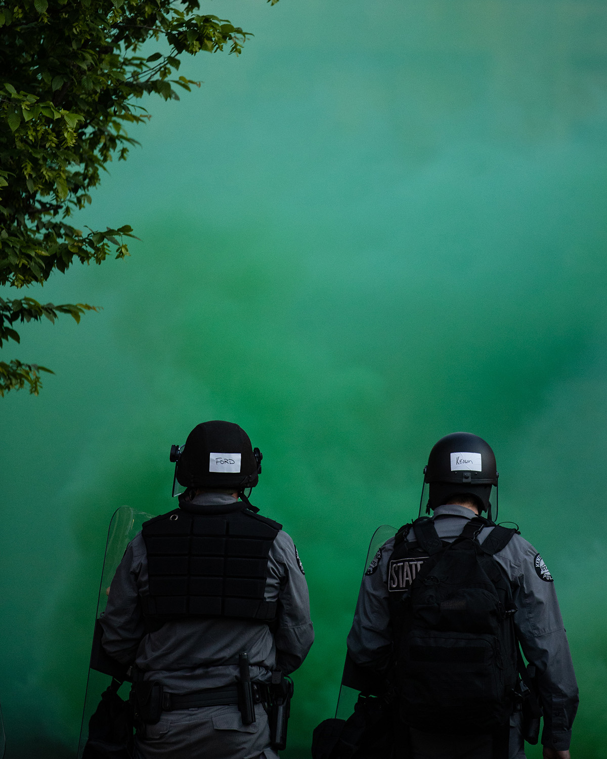 Two police officers stand behind a green-colored gas.