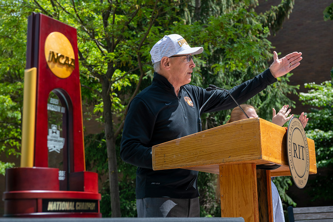 athletics director speaking outdoors at a podium.