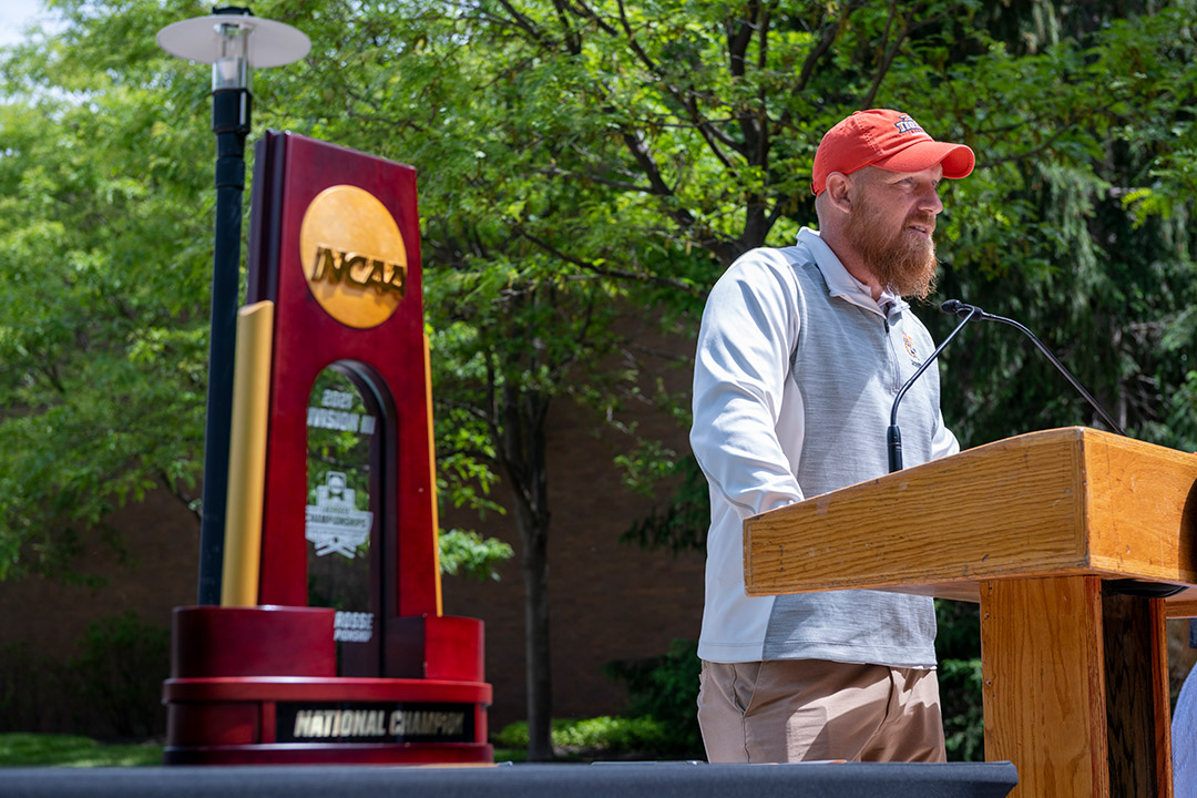 coach speaking outdoors at a podium.