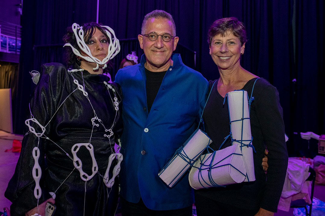 student standing with professor and a woman at a fashion show.