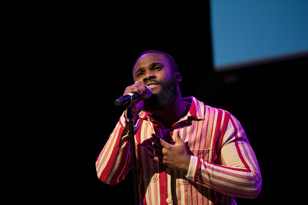 student singing into a microphone on stage.