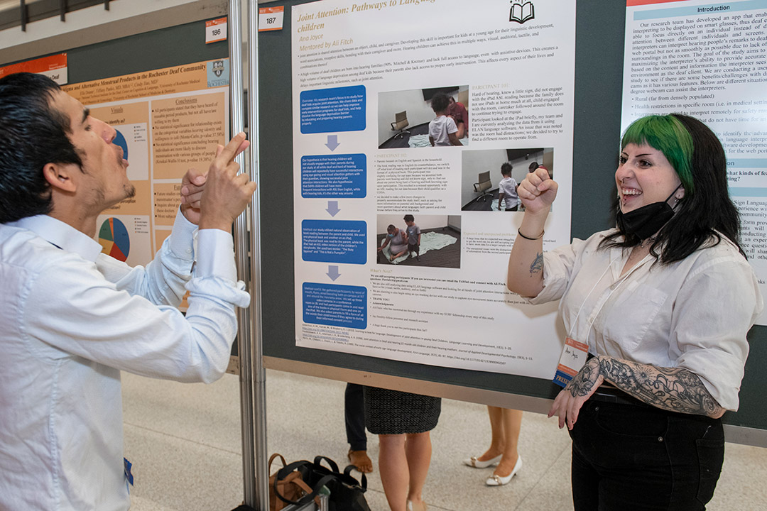 student giving poster presentation in sign language.