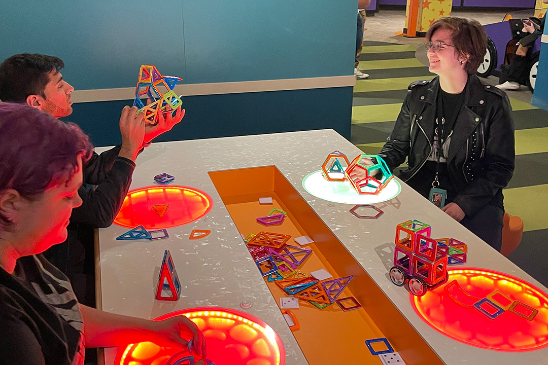 three college students building structures with colorful magnetic shapes.