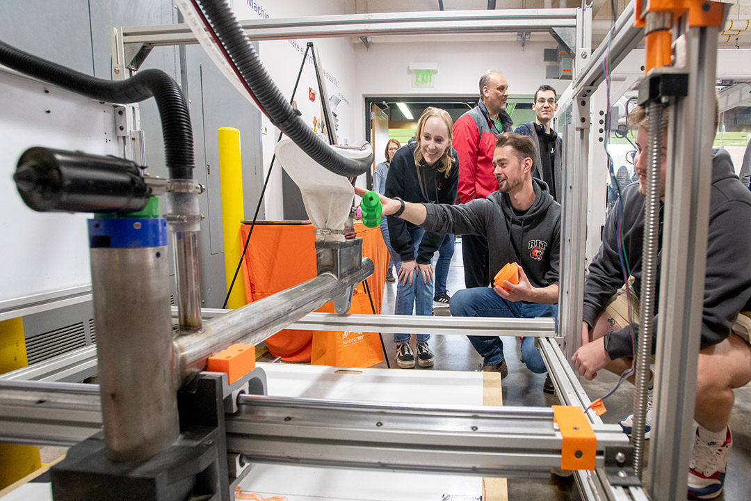 college students demonstrating a 3 D printer.