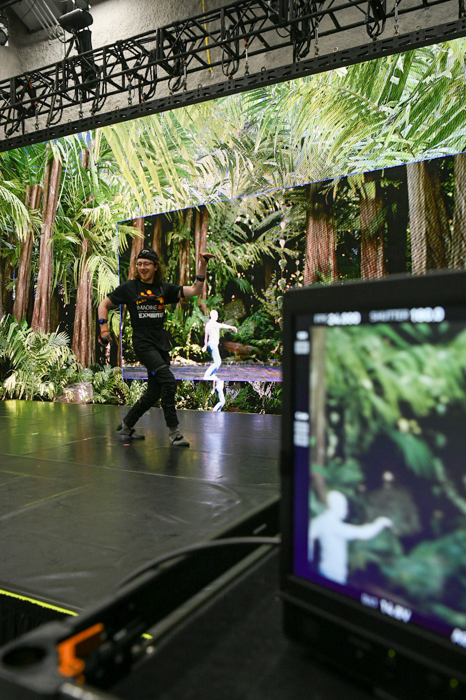 college student walking across a stage with a jungle image in the background.