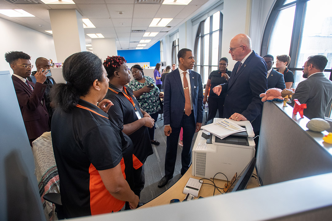 group of people standing next to a printer in an office setting.